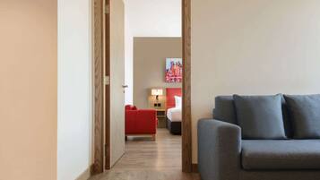 Un pasillo que lleva a una habitación con un sofá rojo y un sofá gris.