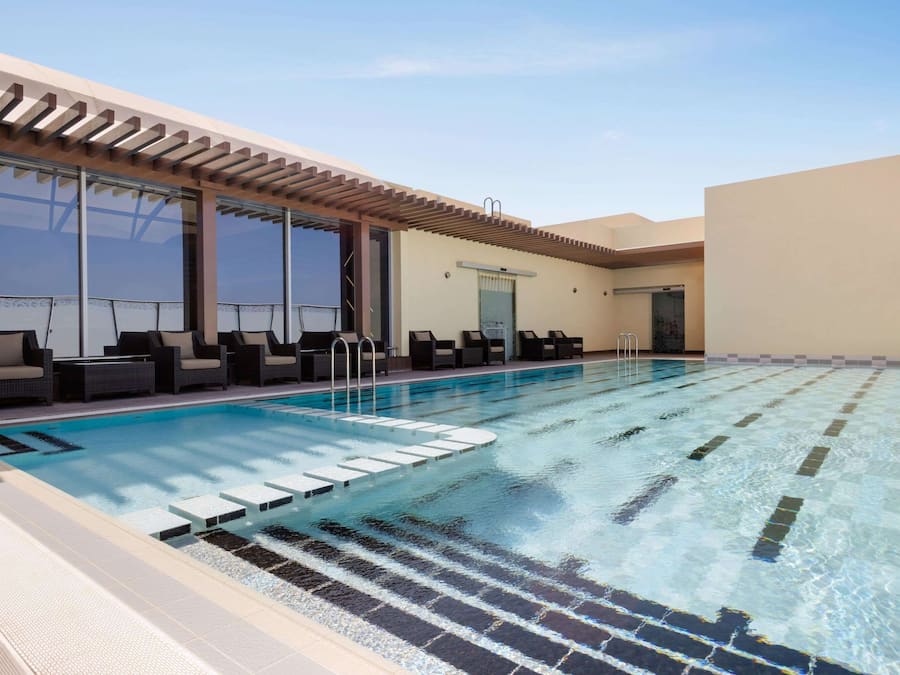 A swimming pool with lounge chairs and a pergola.
