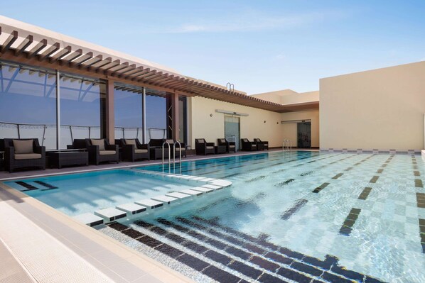Une piscine avec des chaises longues et une pergola.