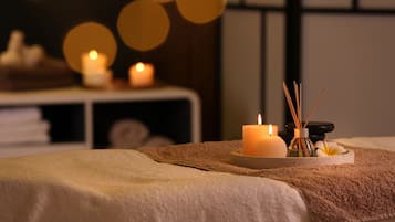 A spa setting with a massage table, candles, and a diffuser.
