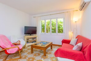 A living room with a television, a red sofa, a wooden coffee table, and a chair.