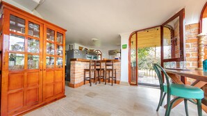 A kitchen with a wooden cabinet, a bar area, and a dining table with chairs.