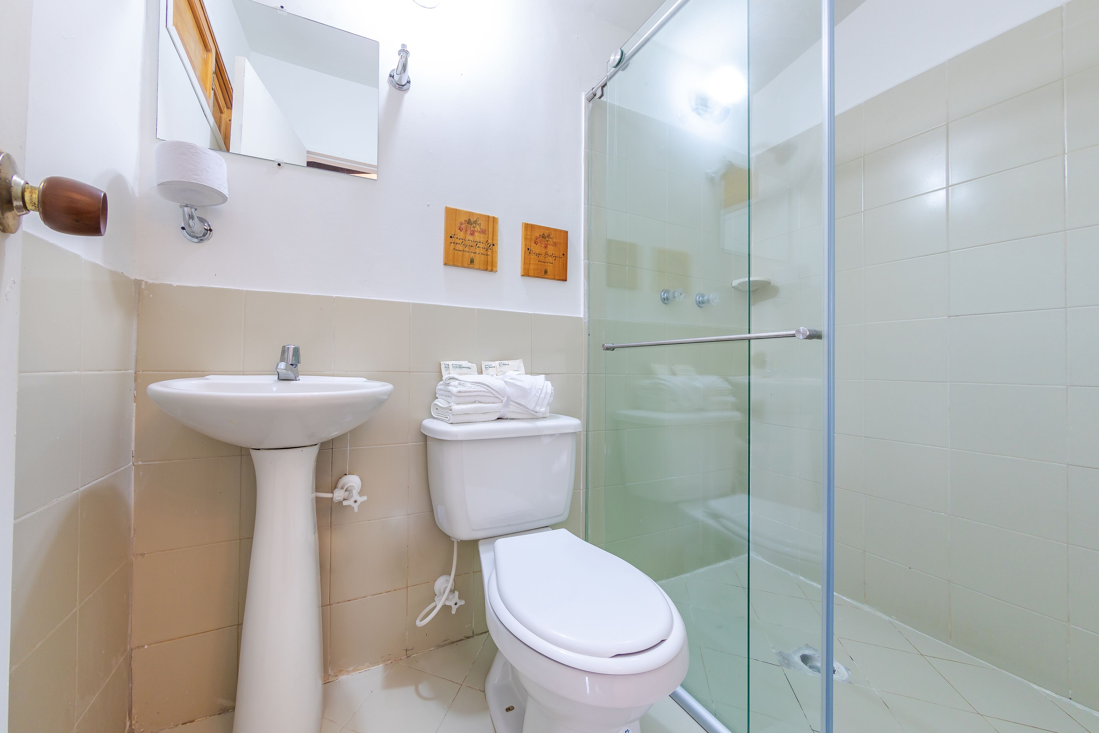 A bathroom with a pedestal sink, toilet, and glass-enclosed shower.