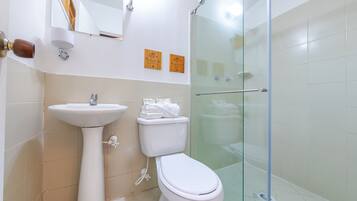 A bathroom with a pedestal sink, toilet, and glass-enclosed shower.