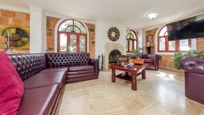 A spacious living room with a large leather sofa, a wooden coffee table, and a fireplace.