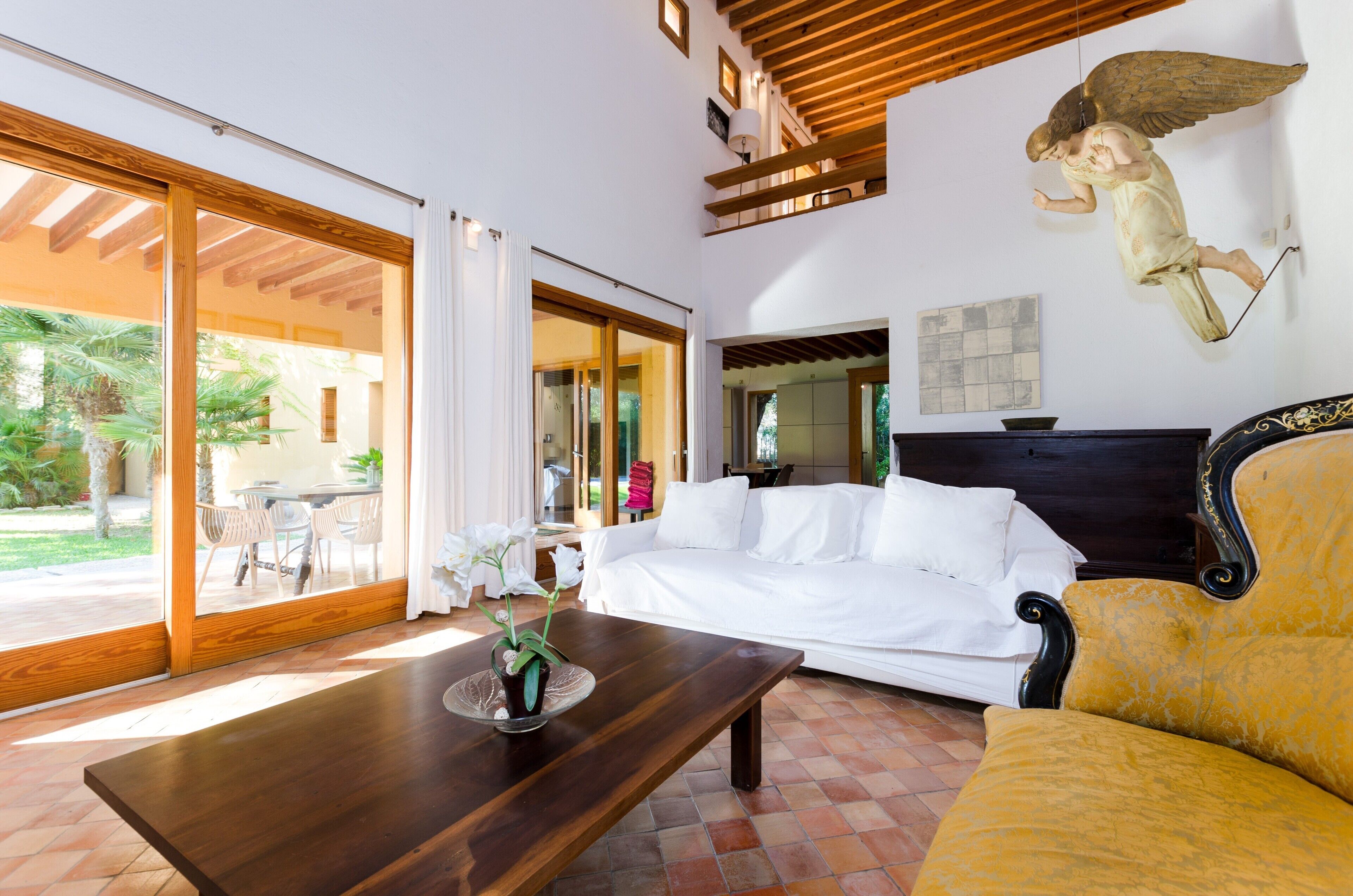 Una sala de estar moderna con un sofá blanco, una mesa de centro de madera con una planta, y un sillón amarillo.