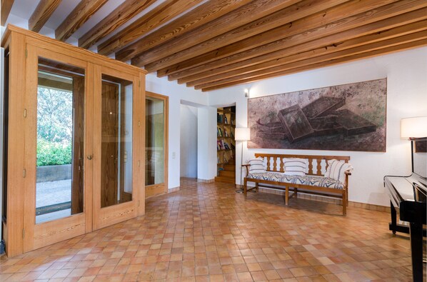 A spacious room with a tiled floor, wooden ceiling beams, a bench, a piano, and a bookshelf. - VILLA SON FLORIANA - House with private pool in Cala Bona Free WiFi (Son Servera)