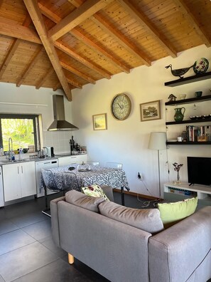 A modern kitchen with a dining table, sofa, and TV.