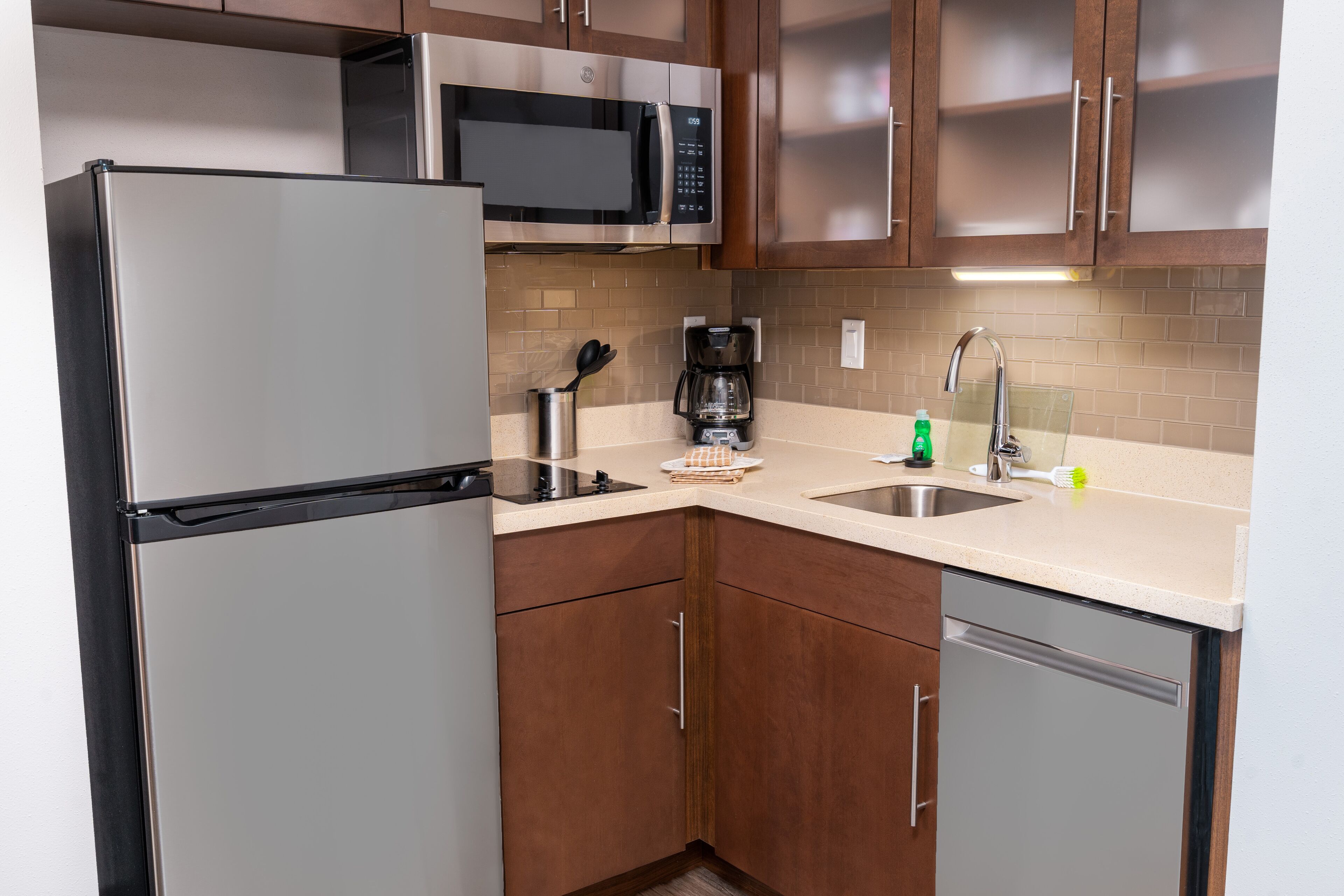 Una cocina moderna con electrodomésticos de acero inoxidable, armarios de madera y una encimera color beige.