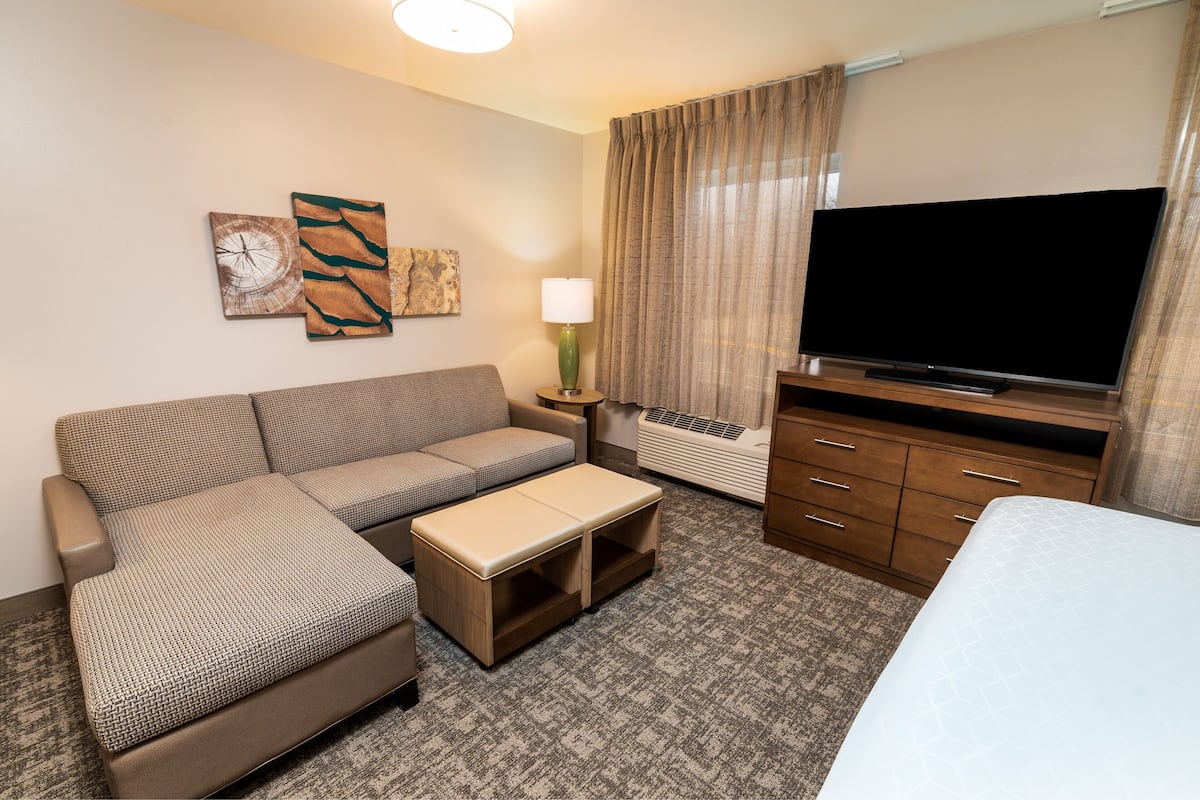Ein Hotelzimmer mit einer Couch, einem kleinen Tisch, einem Fernseher und einem Bett.