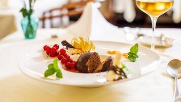 A dessert plate with various fruits and a glass of white wine on a table.