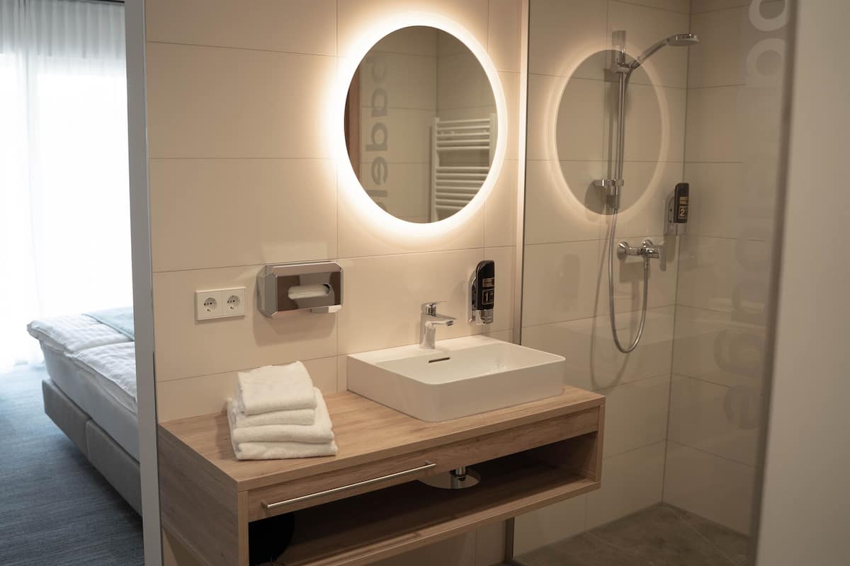 A modern bathroom with a sink, mirror, and shower.