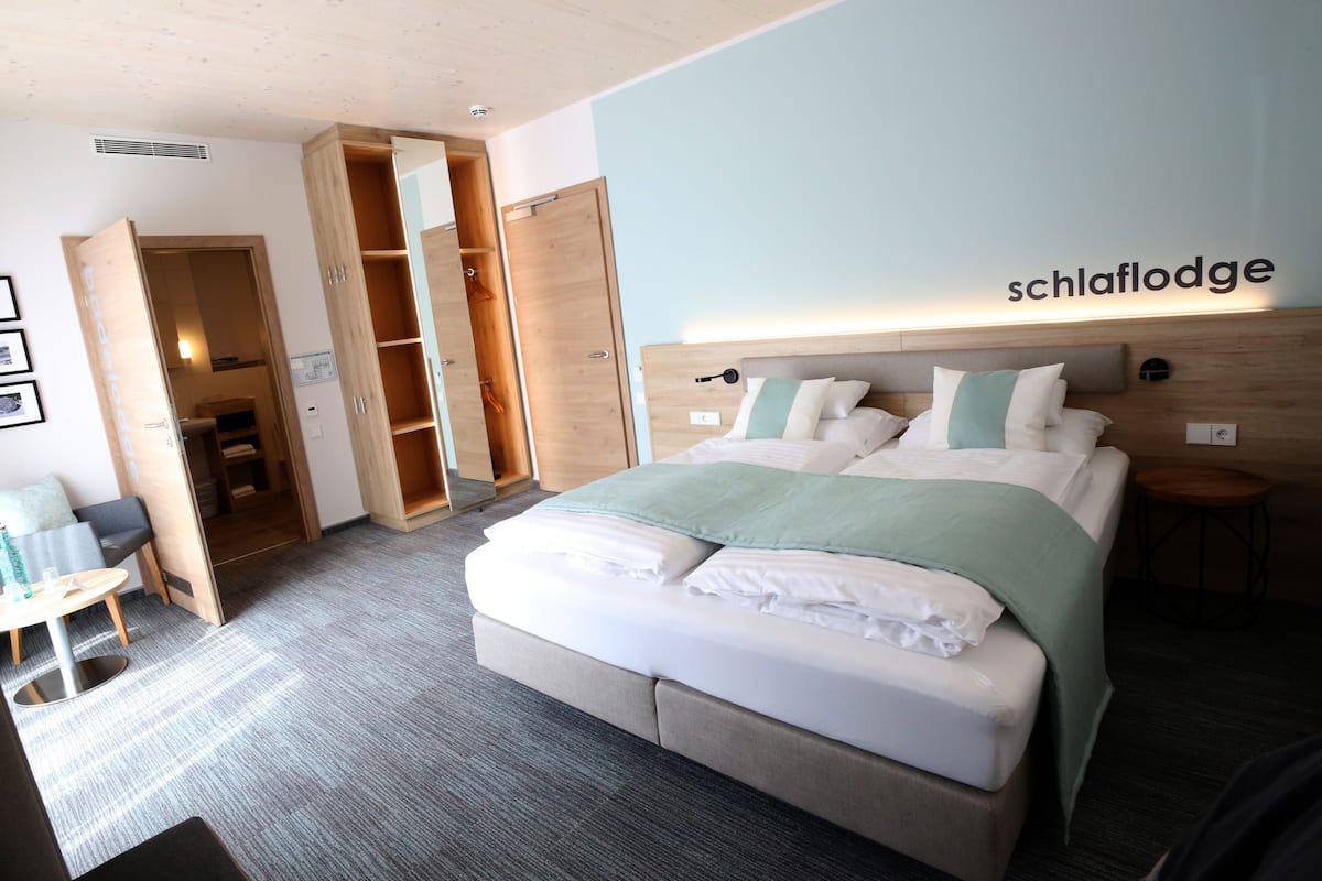 A hotel room with a bed, a desk, and a wardrobe.