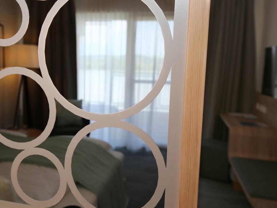 Una habitación de hotel con cama, escritorio y ventana con cortinas.