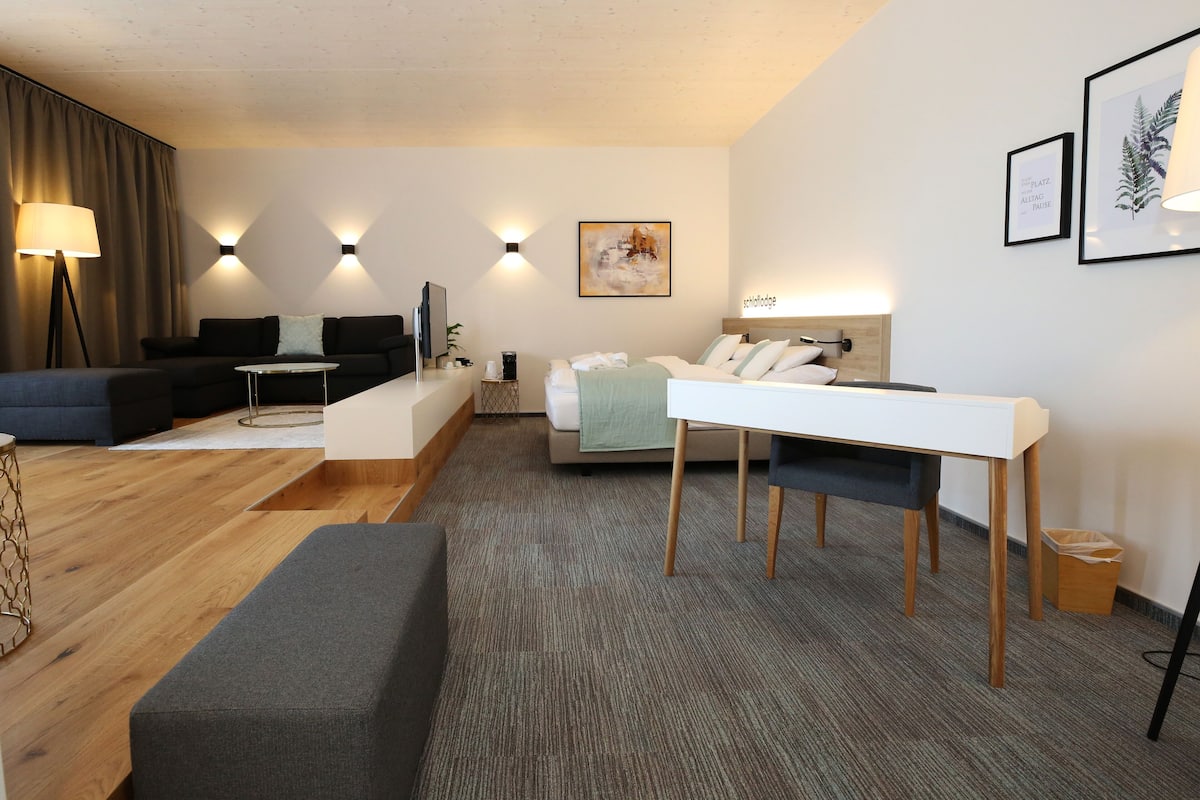 A modern living room with a sofa, a dining table, and a TV.