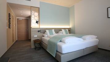 A modern hotel room with a large bed, a bedside table, and a decorative wall panel.