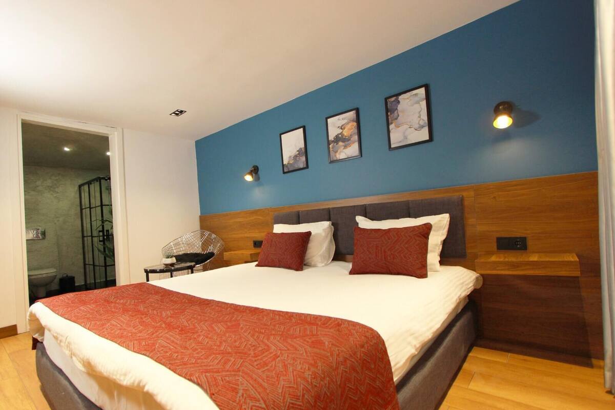 A modern bedroom with a large bed, a wooden headboard, and a blue accent wall.