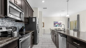 A modern kitchen with dark cabinetry, stainless steel appliances, and a tiled backsplash.