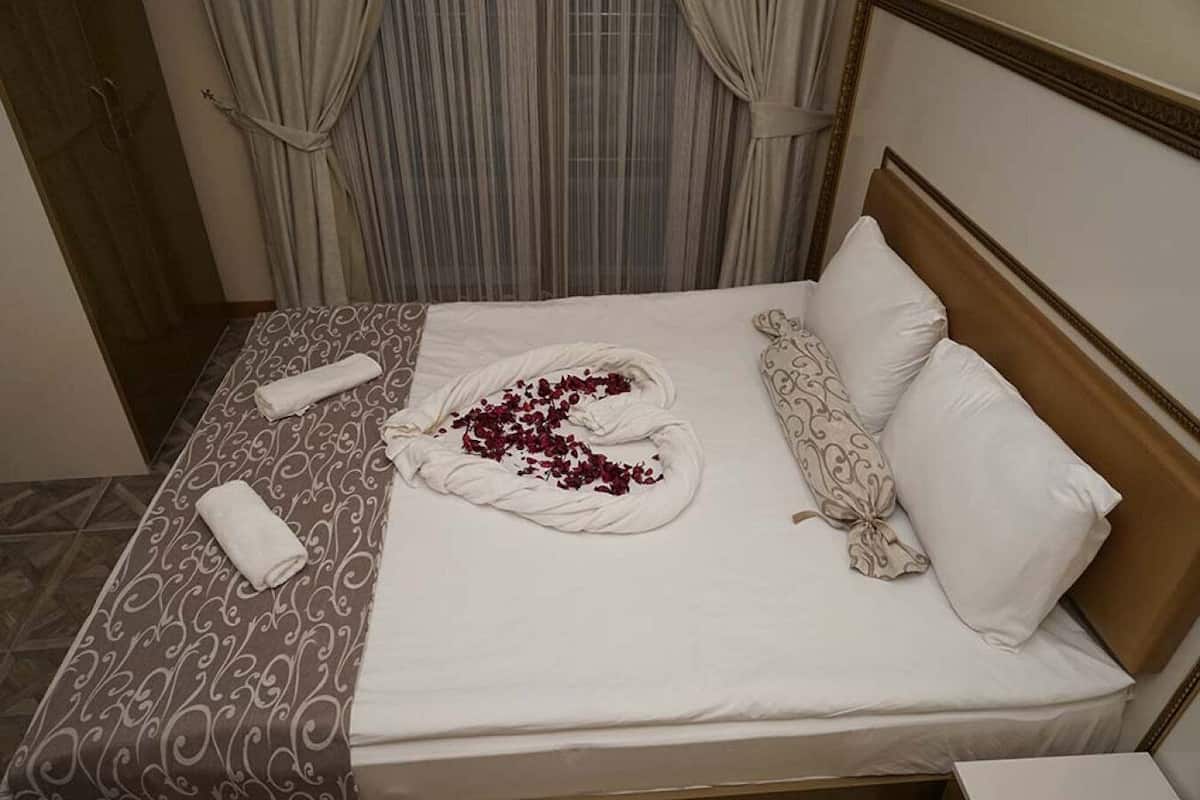 A neatly made bed with a patterned bedspread, a decorative towel, and a pillow with a paisley design.