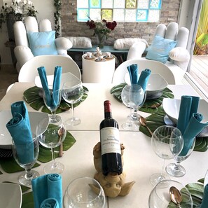 Une table à manger dressée avec des serviettes bleues, des verres à vin et une bouteille de vin.