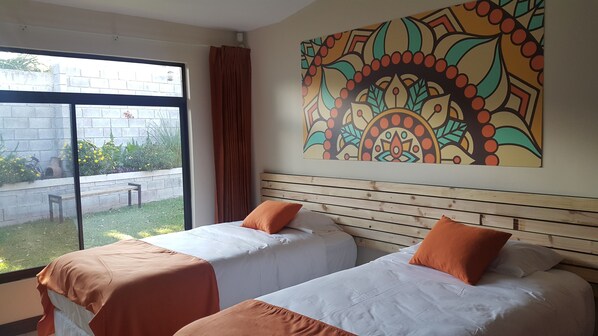 A hotel room with two beds, a large window, and a colorful wall mural. - Ananta Wellness & Retreat (San Rafael)