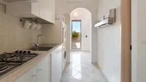 Une petite cuisine équipée d’une cuisinière à gaz, d’un évier et d’un lave-linge.