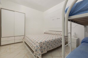 A bedroom with a bunk bed, a wardrobe, and a bedside table with a lamp. - Villetta Playa De Mar by BarbarHouse (San Pietro in Bevagna)