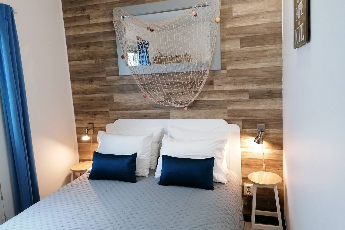 Ein Schlafzimmer mit einem Bett, zwei Nachttischen, einem Hängekorb und einer Holzwand.