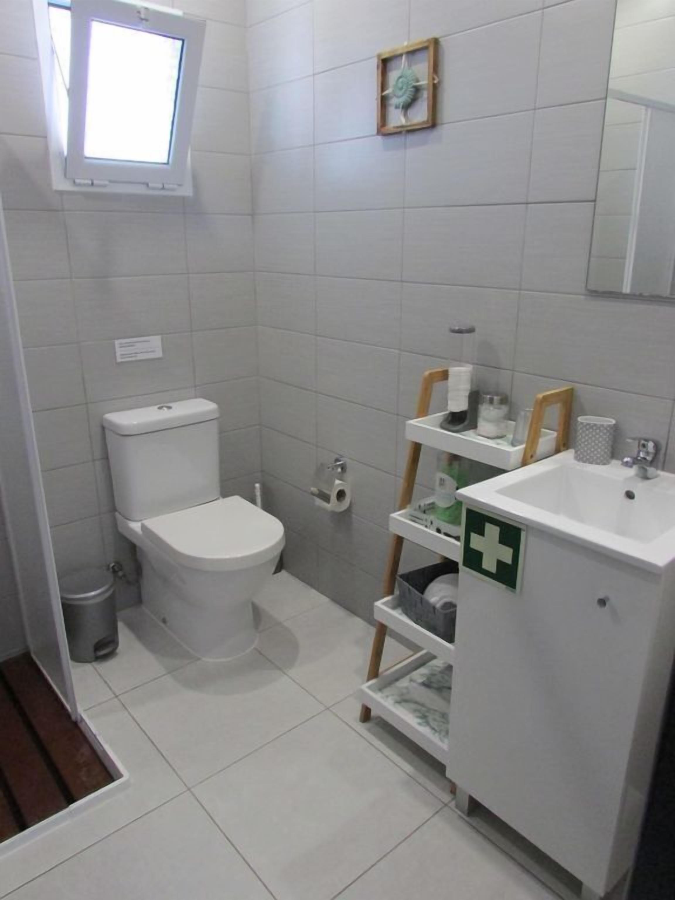 A small, clean bathroom with a toilet, a sink, and a window.