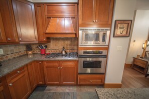A kitchen with wooden cabinets, a stainless steel microwave, a gas stove, and an oven. - Lone Eagle 3026 (Keystone)