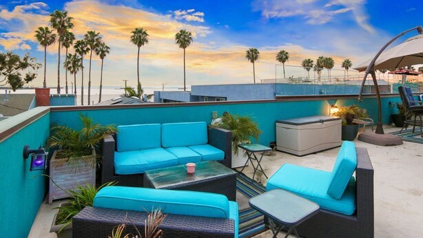 A rooftop terrace with blue seating, a small table, and a potted plant. - Large 4 bedroom, steps from the beach with rooftop patio and jacuzzi. Sleeps 10 (Long Beach)