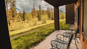 A covered outdoor area with a concrete path, metal chairs, and a view of a forested landscape. - Springs 8805 (Keystone)