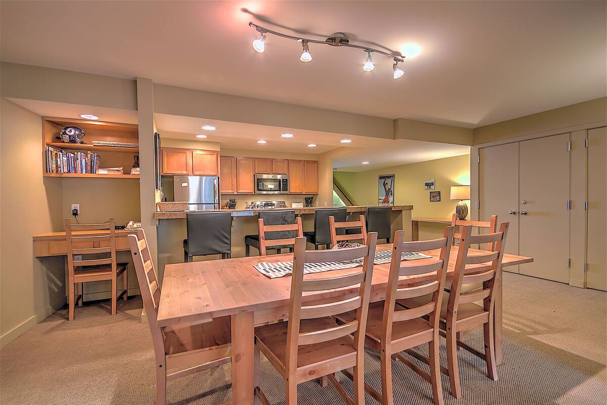 A dining area with a wooden table and chairs, a kitchen with wooden cabinets, and a small island with seating.