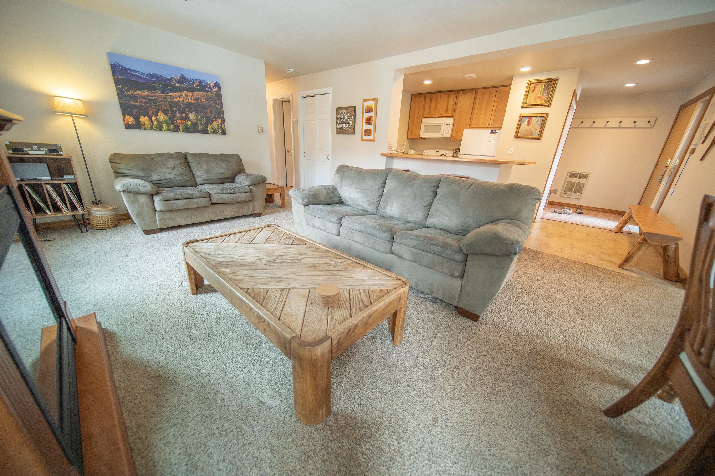 A living room with two grey sofas, a wooden coffee table, a lamp, and a painting on the wall.