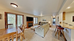 A spacious living area with a fireplace, a dining table, and a kitchen area with bar stools. - Key Condo 2954c (Keystone)