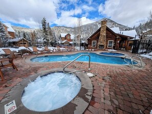 Relax in the resort's central hot tub area, surrounded by a brick patio and a rustic lodge.
