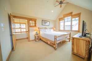 A bedroom with a wooden bed, a nightstand with a lamp, a desk with a computer, and a ceiling fan. - Settlers Creek 6523 (Keystone)