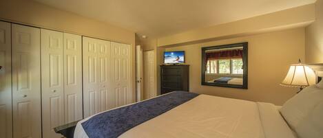 A hotel room with a bed, a television, a dresser, and a mirror.