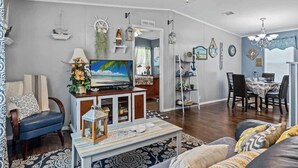 A living room with a television, a dining area, and a kitchen. - 25%Off/Disney 9 mi/Heated Pool/PlayYard/Gym/Courts (Davenport)