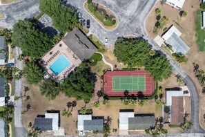 Vue aérienne d’un quartier résidentiel avec une piscine, un court de tennis et plusieurs maisons.