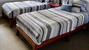 A bedroom with two beds, a ceiling fan, a surfboard on the wall, and a window with curtains. - UPPER UNIT  -1500 sq/ ft - 30 + days ! (Kailua-Kona)
