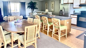 A modern kitchen with a central island, dining area with wicker chairs, and a ceiling fan. - UPPER UNIT  -1500 sq/ ft - 30 + days ! (Kailua-Kona)