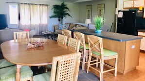 A dining area with a wooden table and chairs, a kitchen counter, a ceiling fan, and a large potted plant. - UPPER UNIT  -1500 sq/ ft - 30 + days ! (Kailua-Kona)