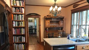 A kitchen with a central island, wooden bookshelves, and a chandelier. - The Federal Quarters (St Marys)