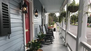 A porch with rocking chairs, potted plants, and hanging planters. - The Federal Quarters (St Marys)
