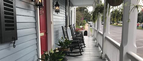 En veranda med gungstolar, krukväxter och hängande blomkrukor.