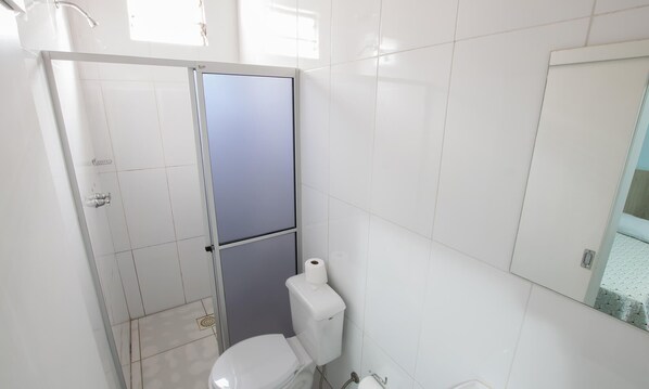 A compact bathroom with a toilet, a shower stall, and a toilet paper holder. - Hotel Conda (Chapecó)