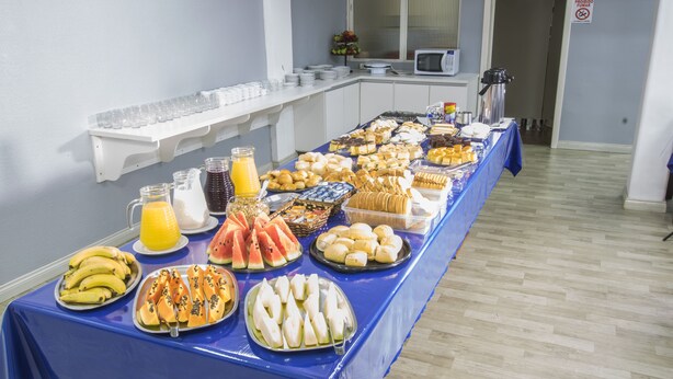A buffet table with various food items and beverages, a microwave, and a sign prohibiting smoking. - Hotel Conda (Chapecó)