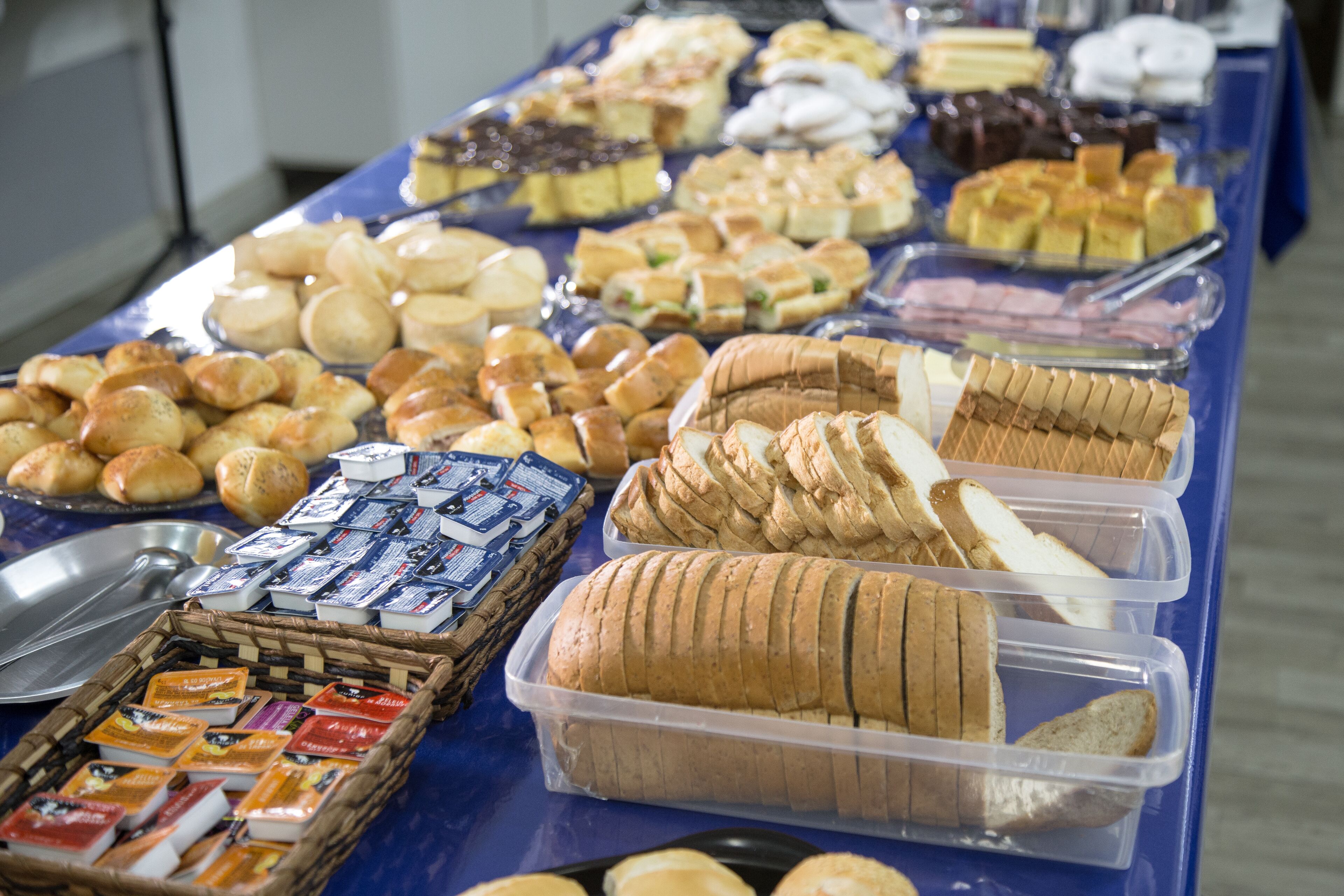 A buffet table with various food items including bread, pastries, and cheese.