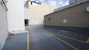 A parking area with marked disabled parking spaces, a fire hydrant, and a building with a brick facade. - Hotel Conda (Chapecó)
